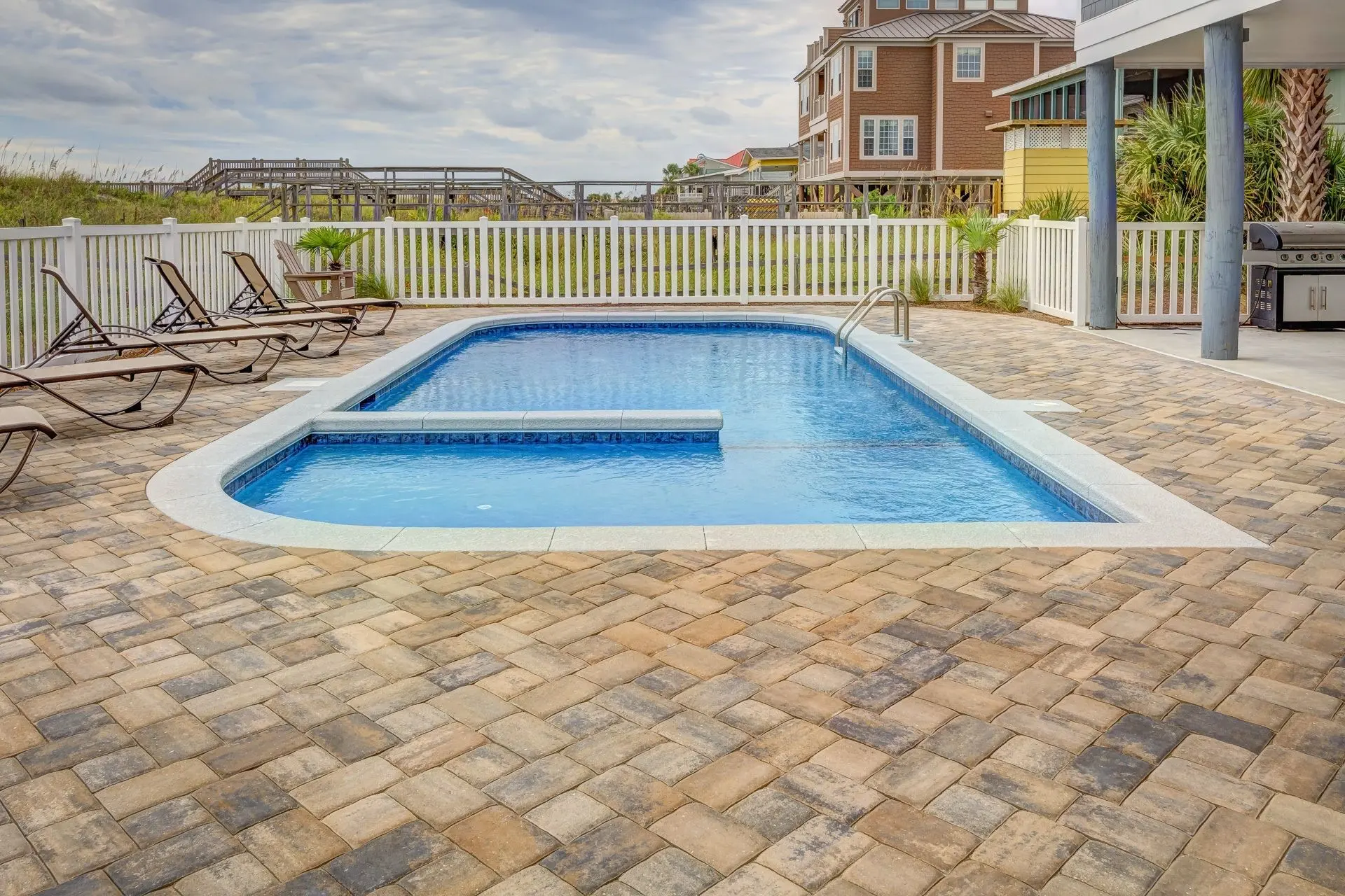 A residential pool with clear blue water and a pale deck